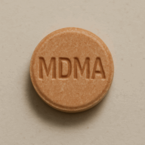 Close-up of a round orange MDMA tablet on a neutral background.